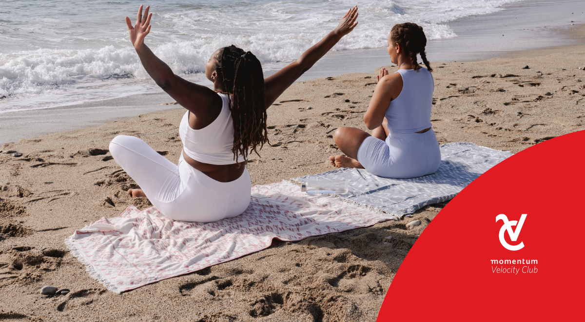 Two young women meditating and doing yoga on the beach.