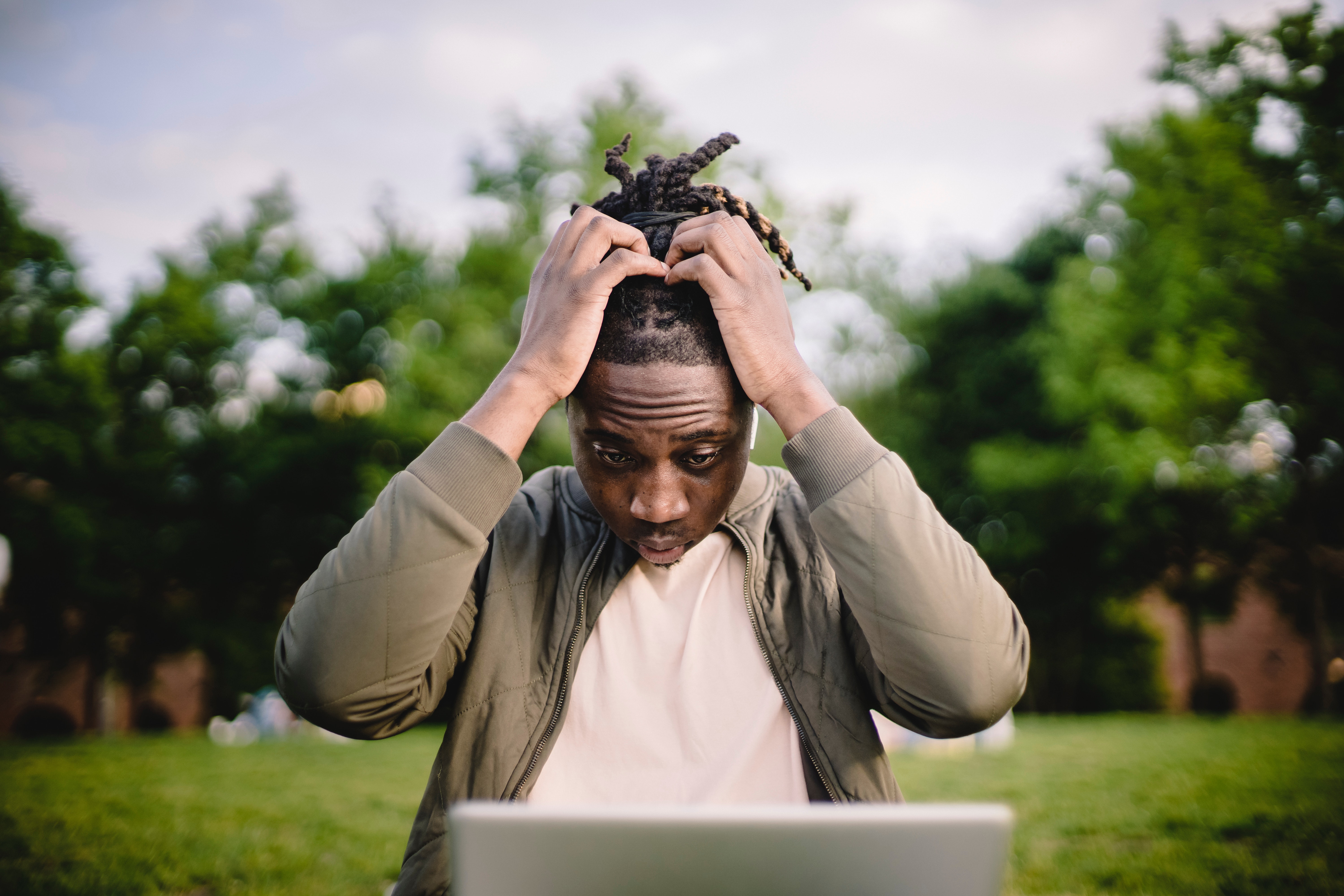 Image of an African man with dreadlocks with his hands in his head in despair when he thinks about his financial future.