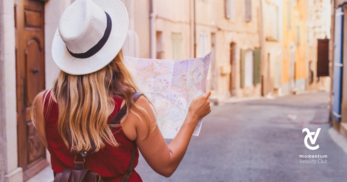 A woman walking down a street holding a map in her hands.