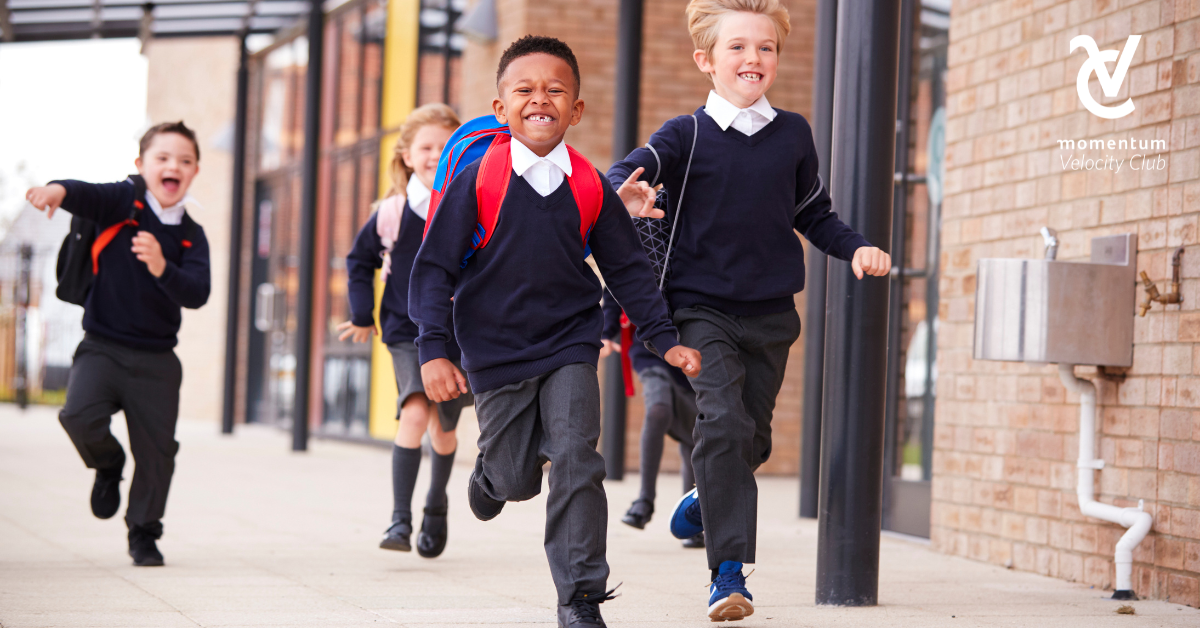 A group of young children smiling, running and excited for their first day of school.