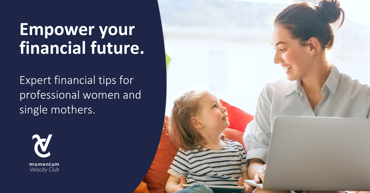 A mom sits on a red couch with a laptop on her lap, smiling at her young daughter who’s seated next to her.