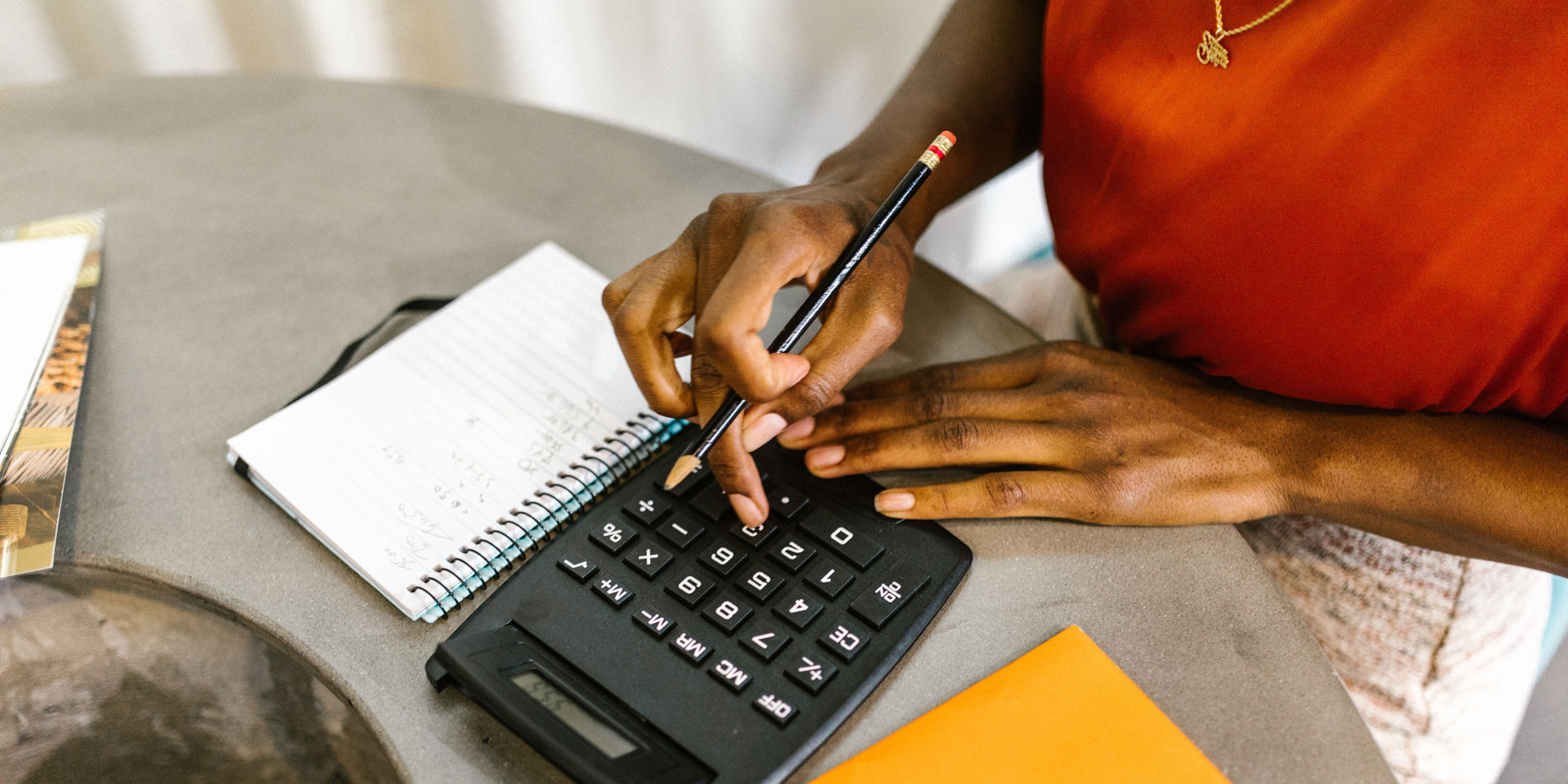A young woman working on a calculator. Next to her is her budget diary.
