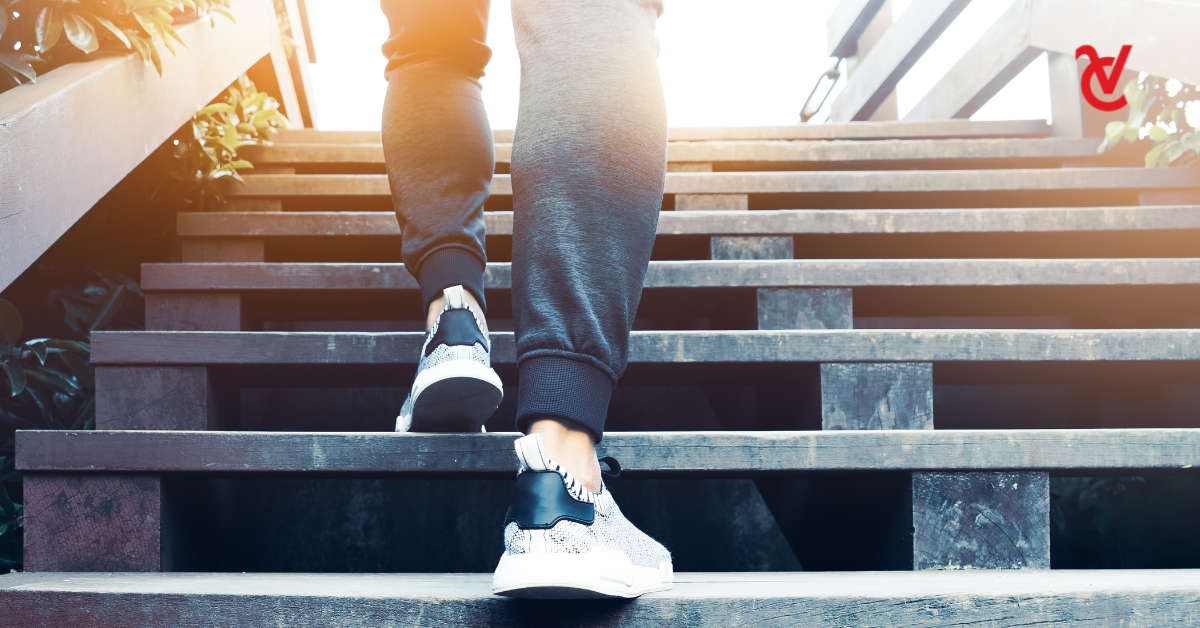 A man wearing trainers climbing wooden stairs.
