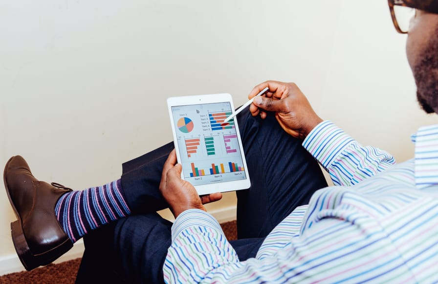 Businessman sitting and reviewing investment graphs on his tablet device.