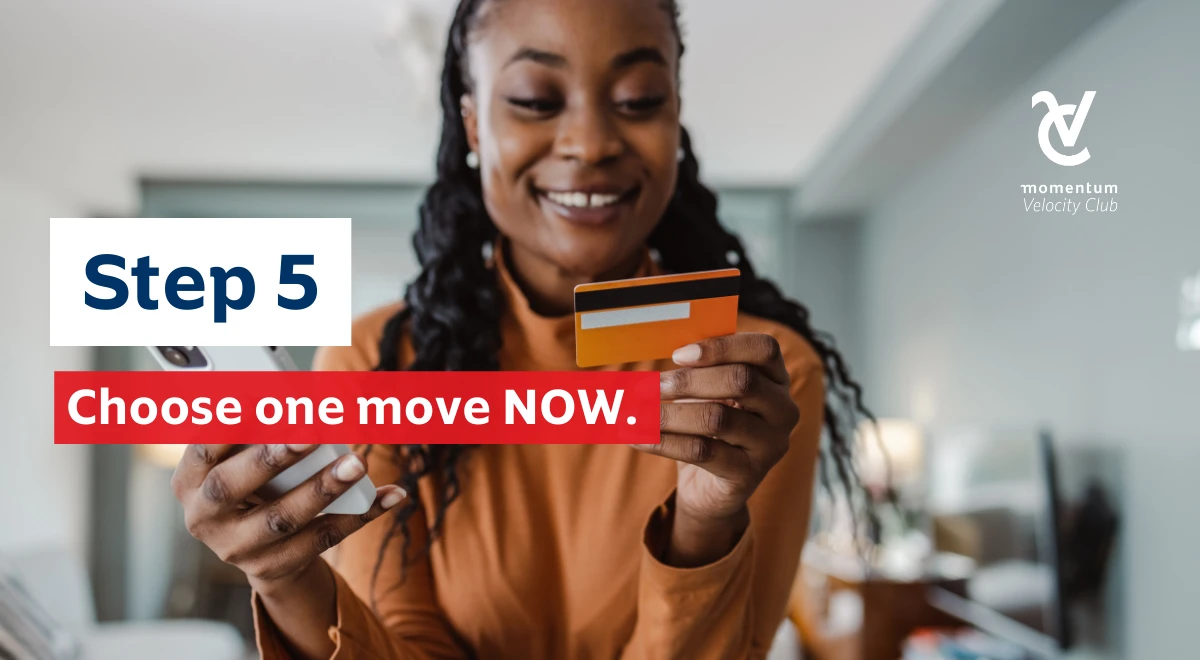 A woman looking at her credit card with a cell phone in hand, smiling with confidence because she’s made a good financial decision that will set her up for success in 2026.