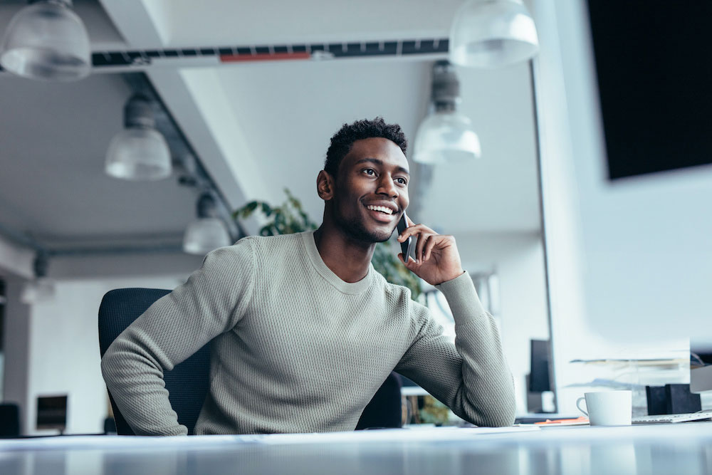 Man in a casual grey sweater talking on his cell phone.